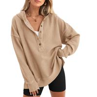Woman wearing a beige oversized sweater with black shorts.